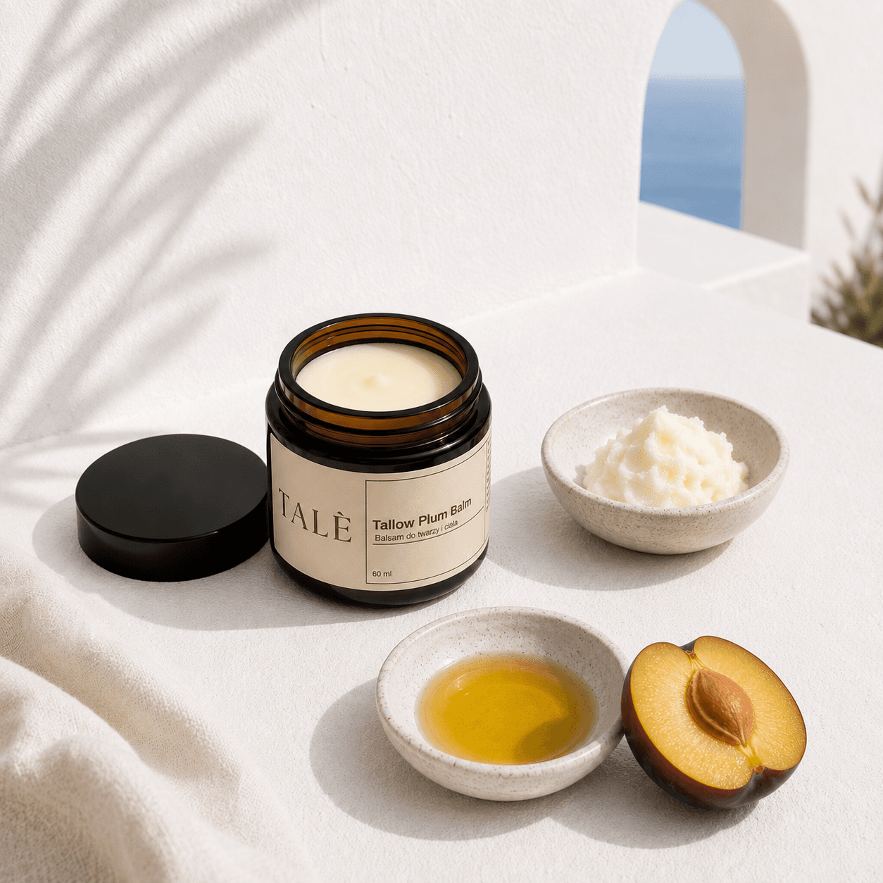Otwarty słoik balsamu Tallow Plum Balm obok miseczki łoju, oleju i śliwki